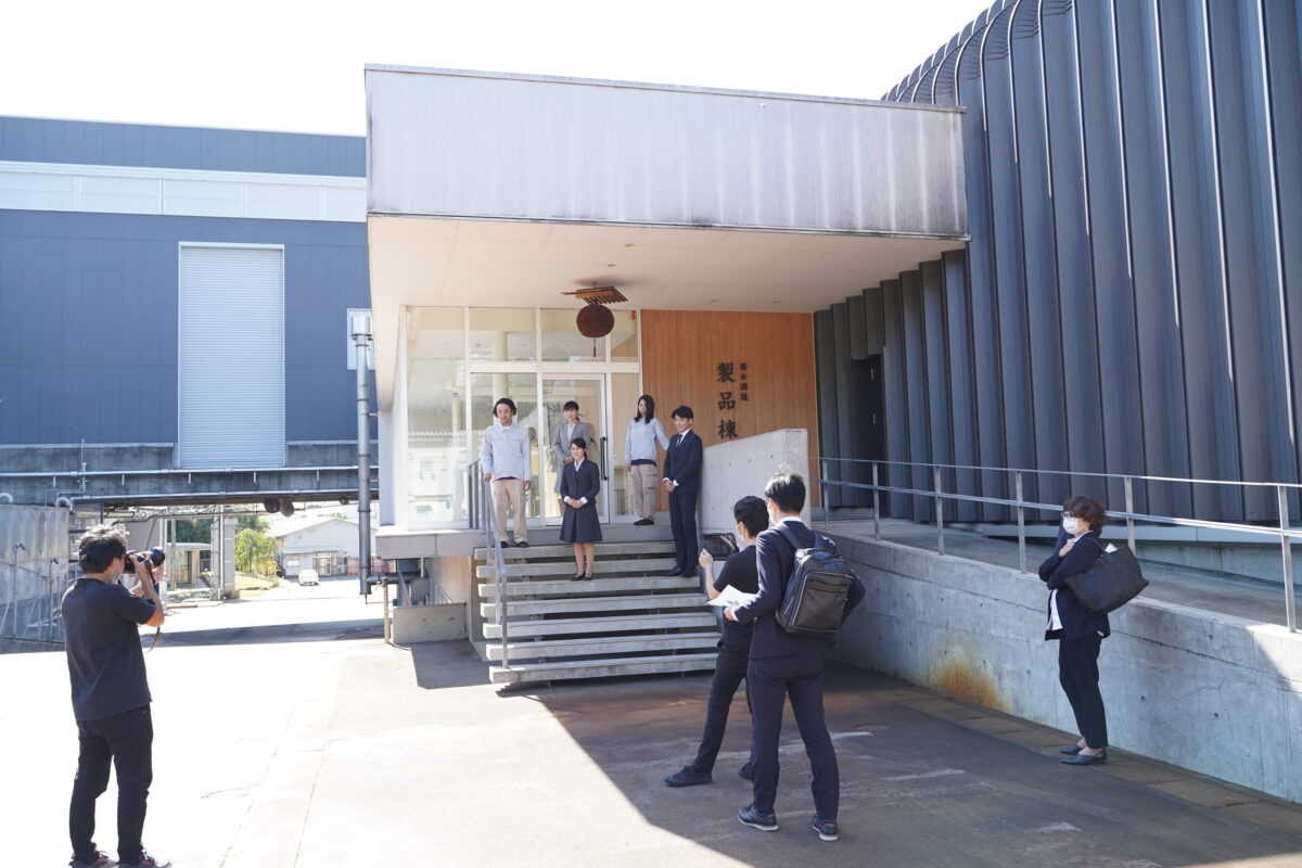 製品棟前で行った先輩社員の集合写真の撮影シーン